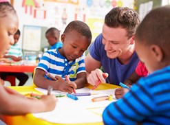 A preschool teacher colors with preschool students